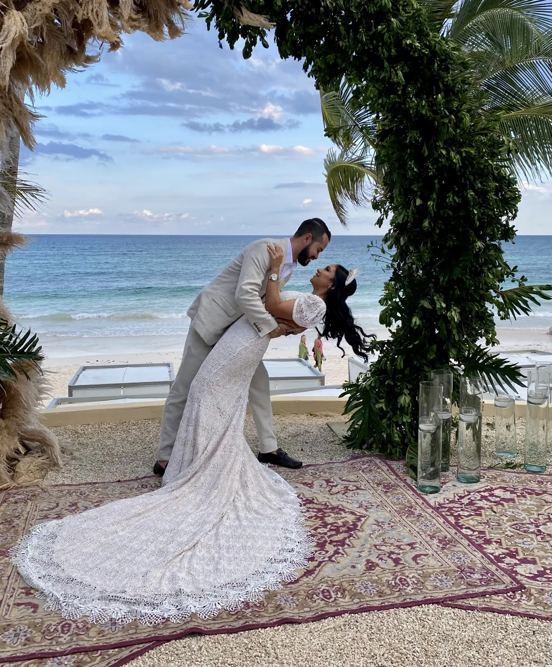 Pareja en ceremonia frente al mar con arco de palmeras y velas