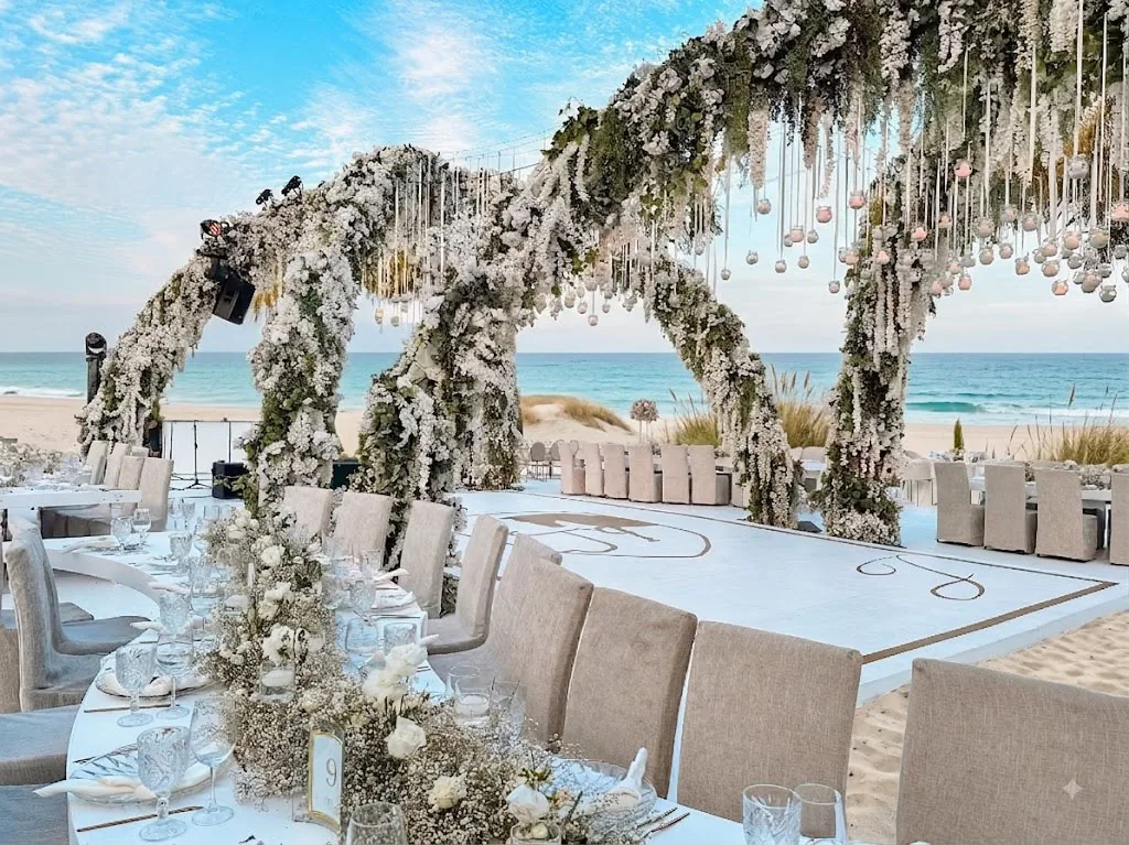 Recepción en playa con arcos florales y mesas elegantes frente al océano