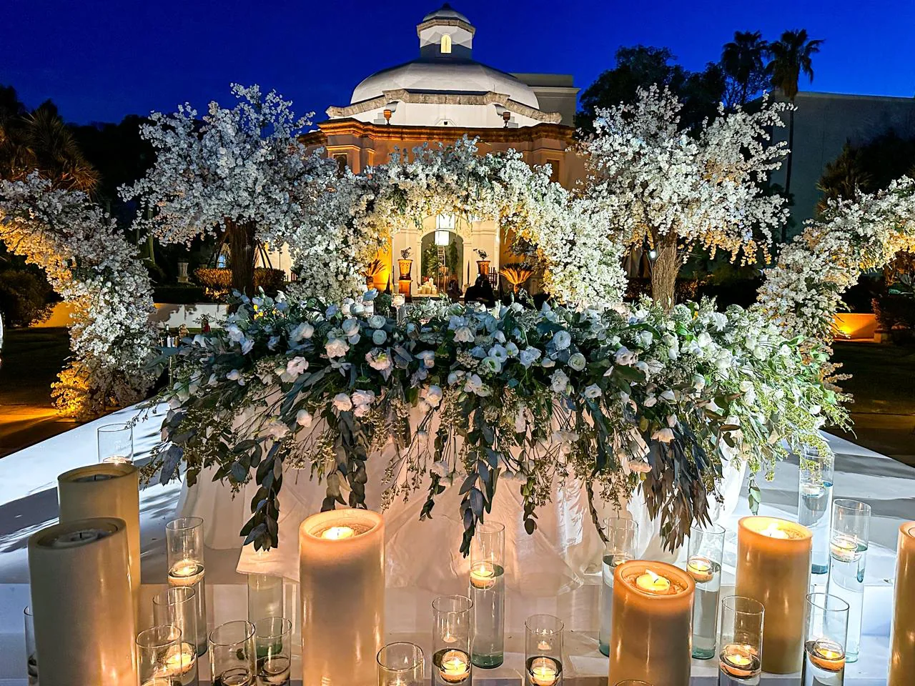 Ceremonia nocturna en hacienda con arco floral blanco y velas