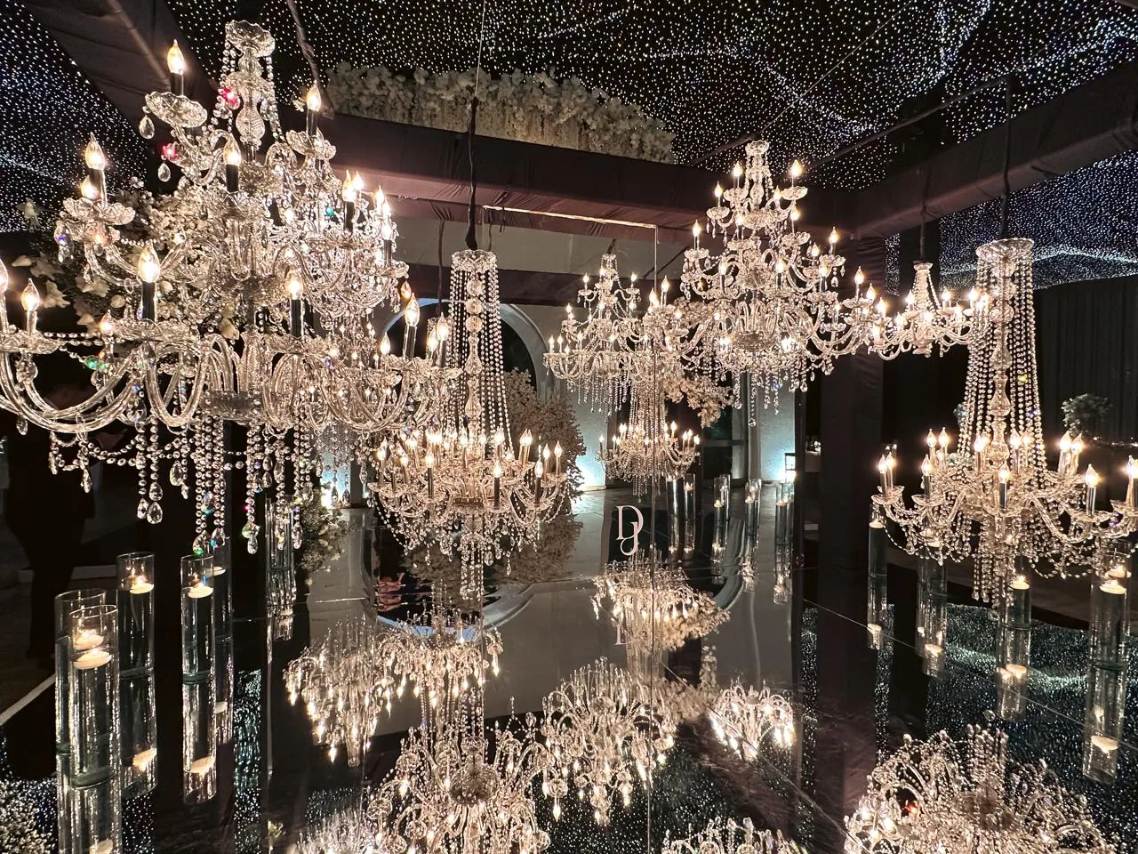 Recepción con múltiples candelabros de cristal reflejados en piso espejo